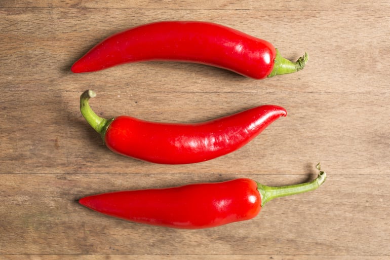 Selection of fresh red chilli on a wooden kitchen work surface