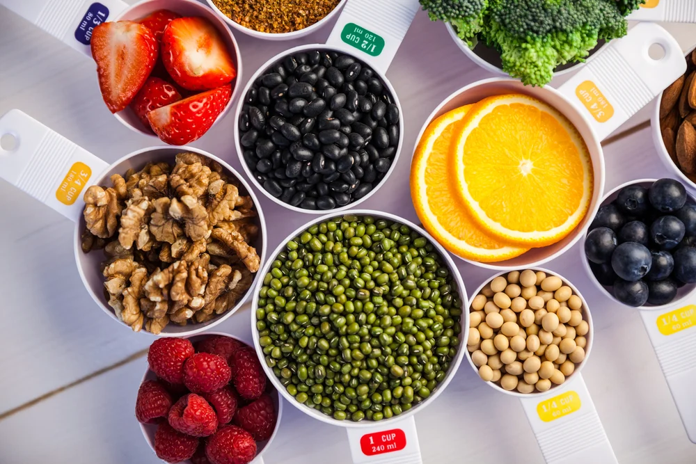 Portion cups and spoons of healthy ingredients on wooden table